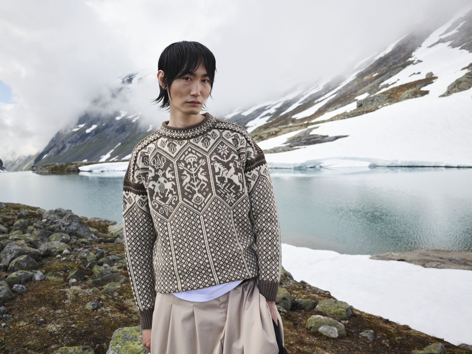 Model standing by glacier wearing wool jumper