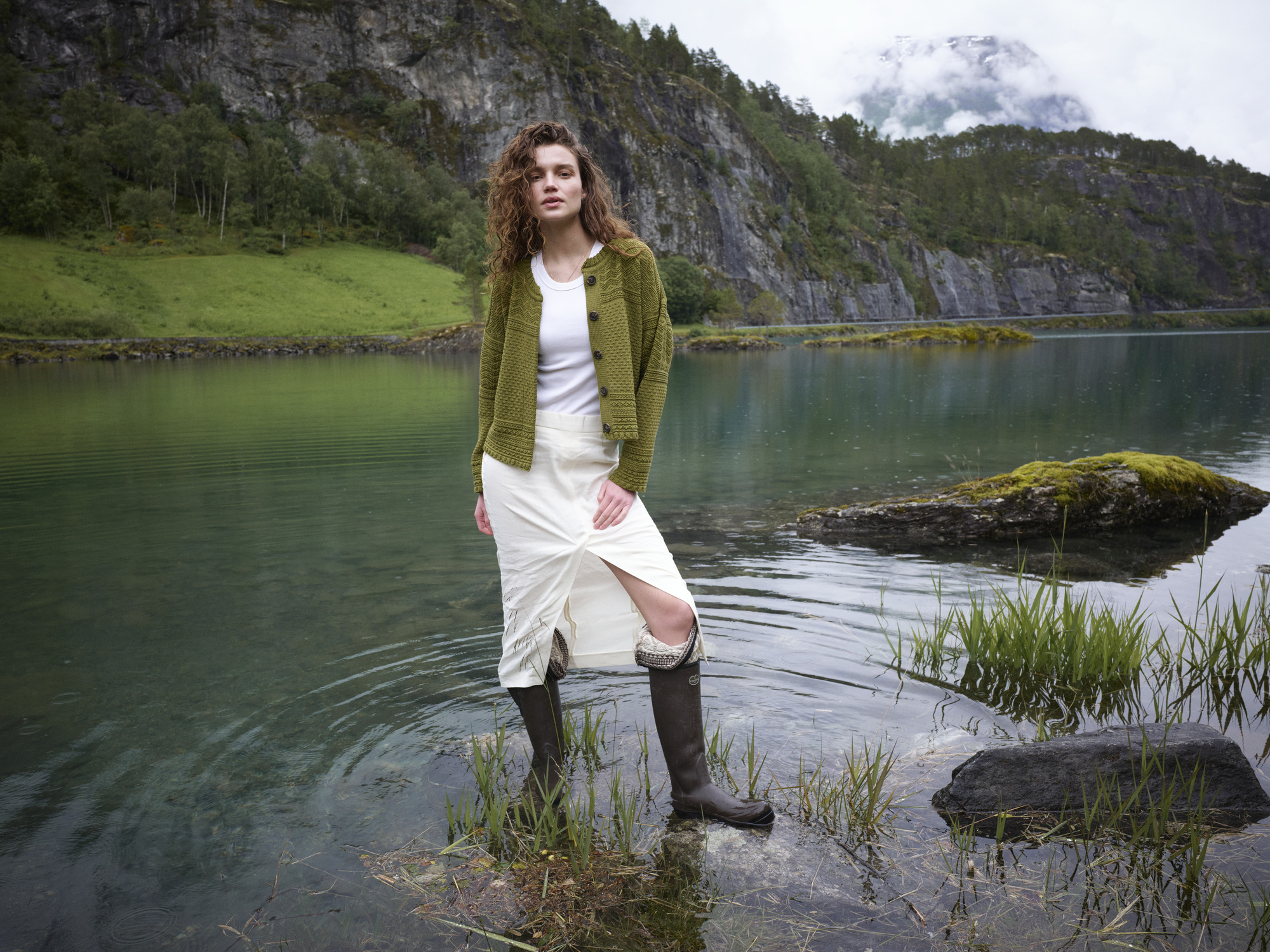 Female model standing in a Norwegian lake wearing a wool sweater