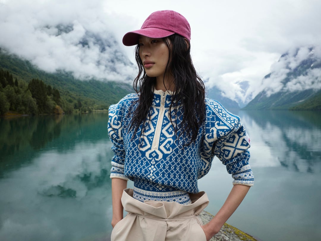 Woman standing in front of Norwegian fjords backdrop in Leknes women's sweater.
